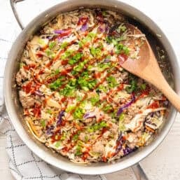 Egg roll in a bowl recipe ready to serve from a skillet with siracha drizzled all over it.