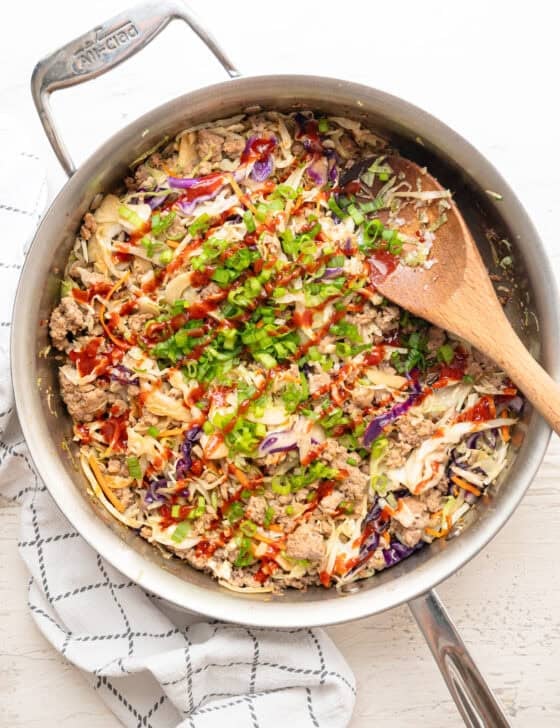 Egg roll in a bowl recipe ready to serve from a skillet with siracha drizzled all over it.