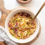 Egg roll in a bowl served in a white bowl on a wooden cutting board.