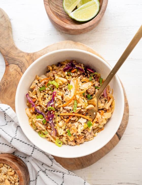 Egg roll in a bowl served in a white bowl on a wooden cutting board.