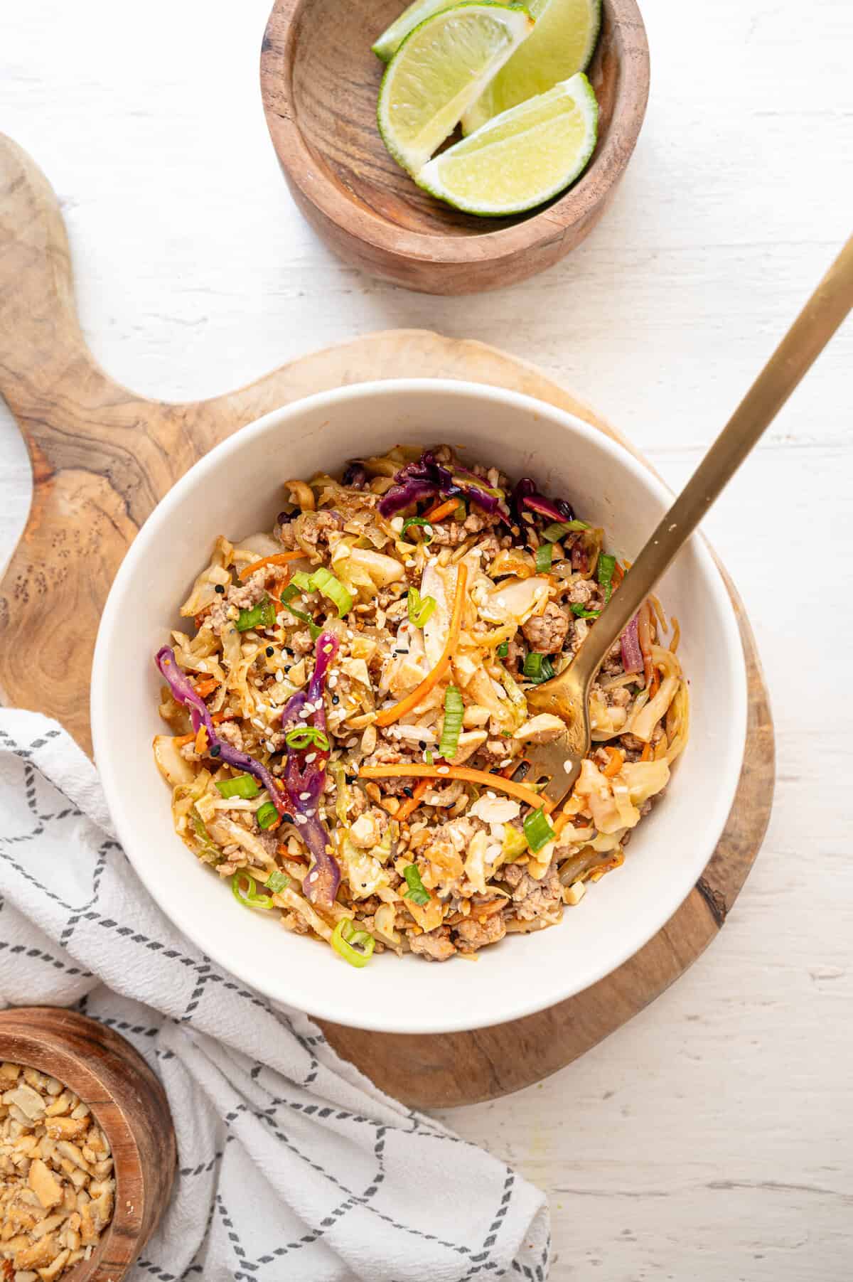 Egg roll in a bowl served in a white bowl on a wooden cutting board.