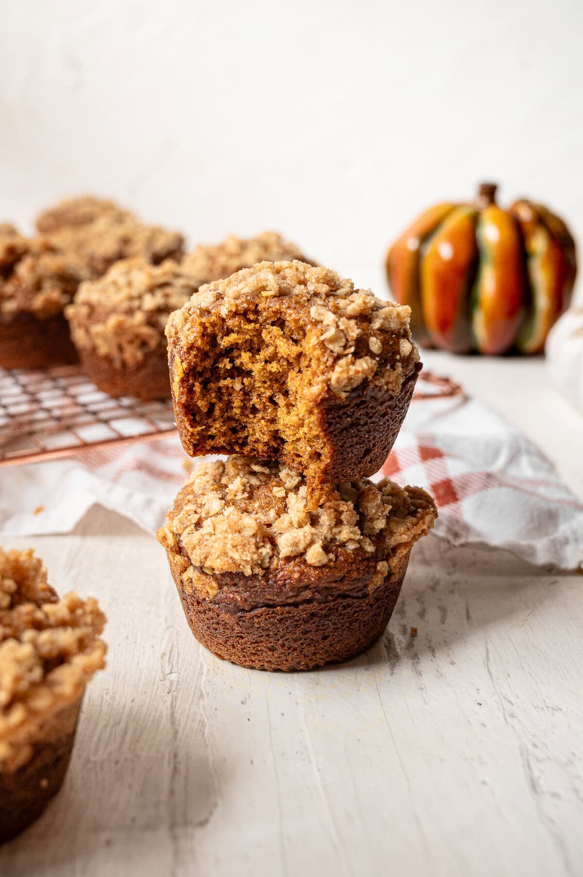 Two pumpkin spice muffins with crumble topping stacked on top of each other.