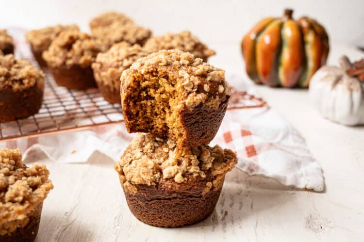 A pumpkin spice muffin with a bite missing stacked on top of another muffin.