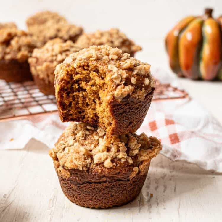 A pumpkin spice muffin with a bite missing stacked on top of another muffin.