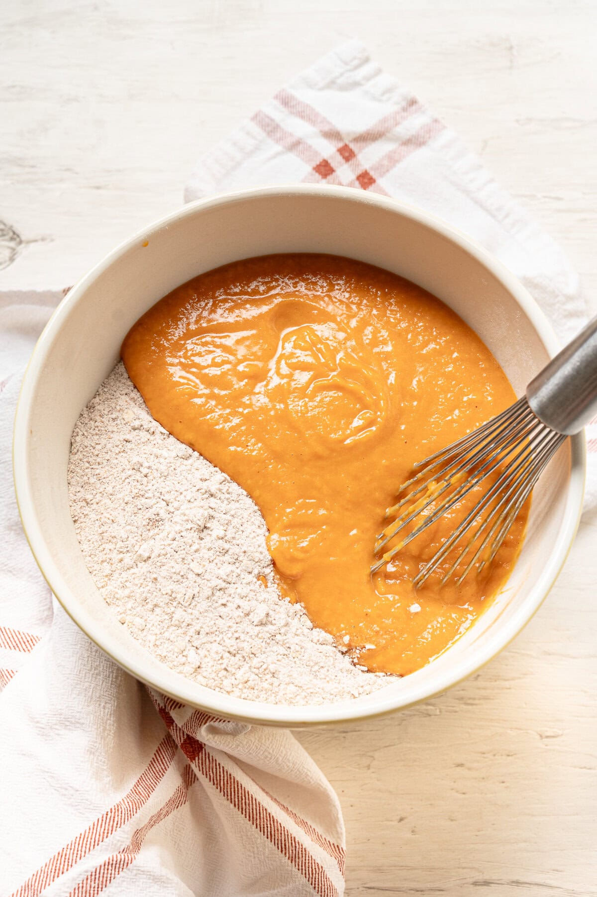 Wet and dry ingredients being mixed together for pumpkin spice muffins.
