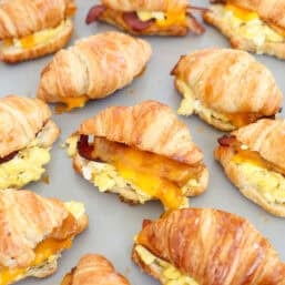 A baking sheet of croissant breakfast sandwiches straight from the oven.