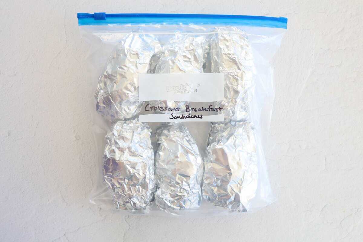 A freezer bag with foil-wrapped sandwiches labeled croissant breakfast sandwiches.