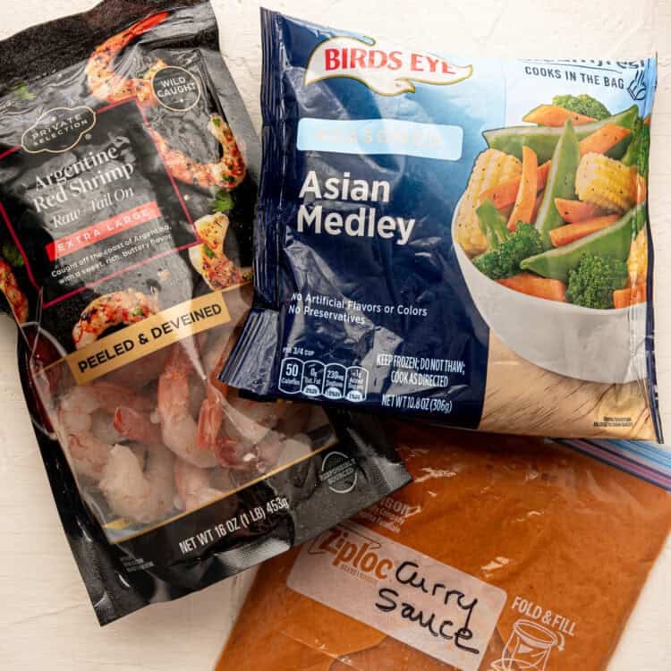 Store-bought bags of frozen shrimp and stir-fry veggies along with a freezer bag labeled curry sauce.