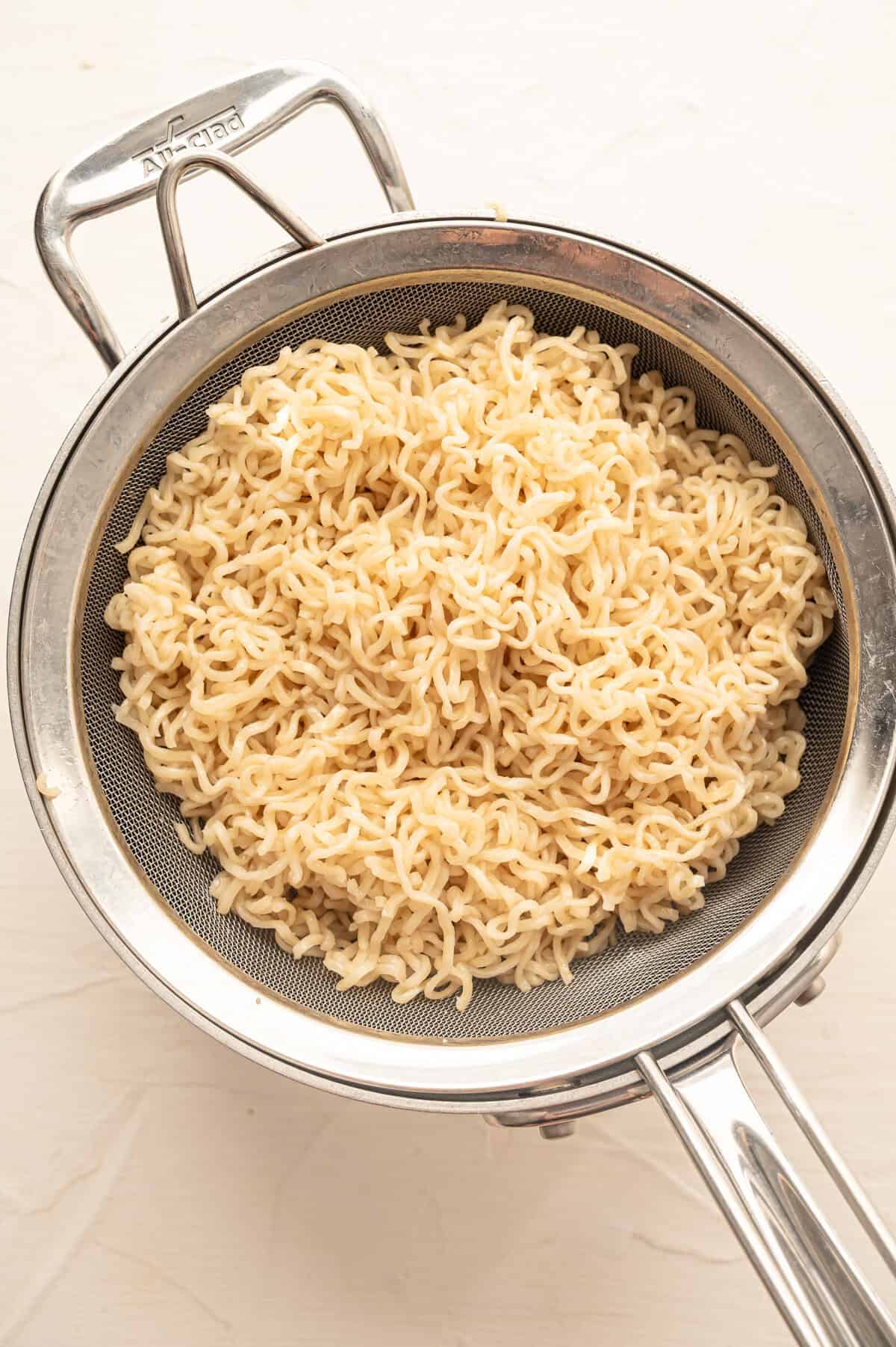 Ramen noodles draining in a colander.