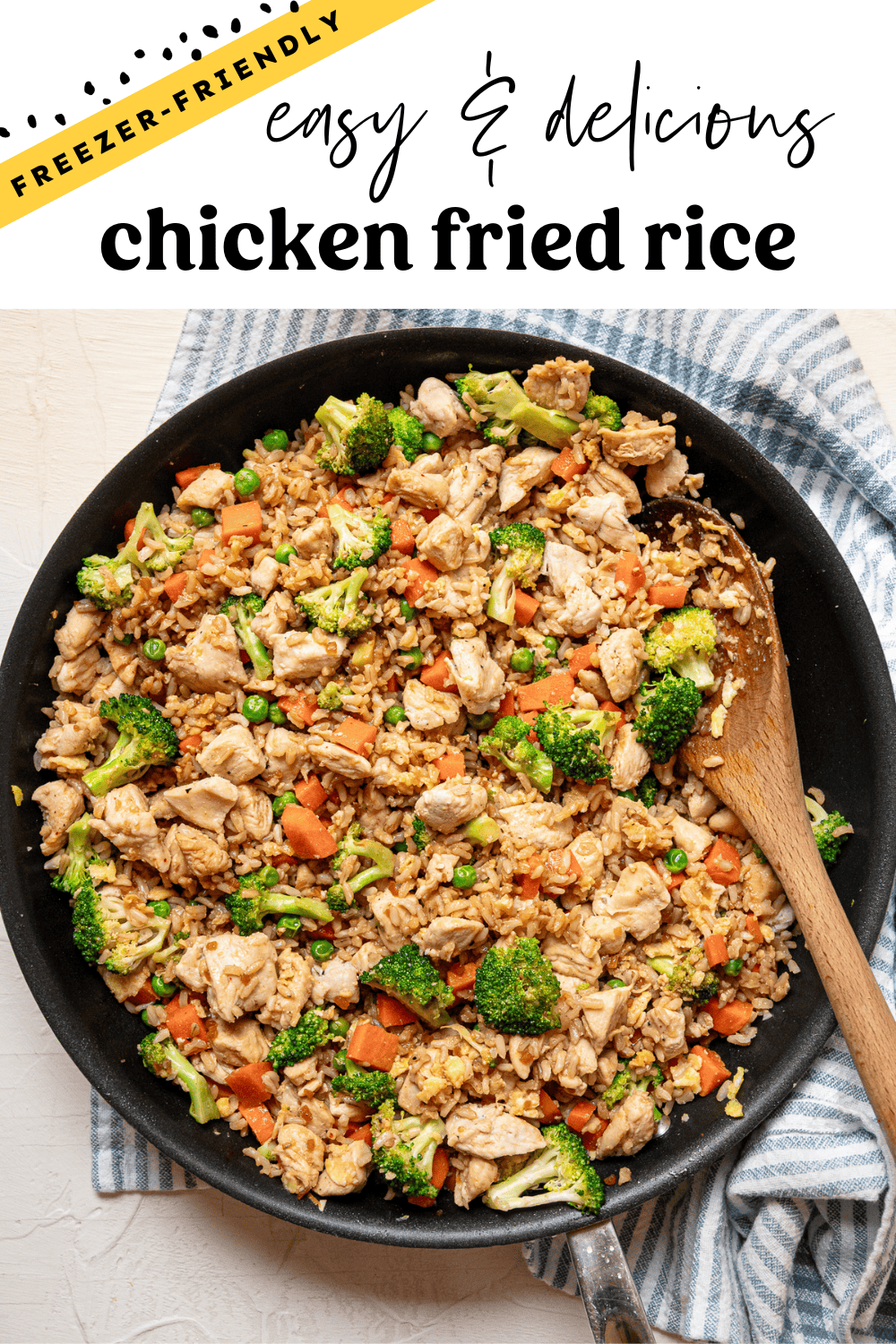 Chicken fried rice served with a wooden spoon out of a skillet.