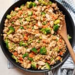 Chicken fried rice served with a wooden spoon out of skillet.