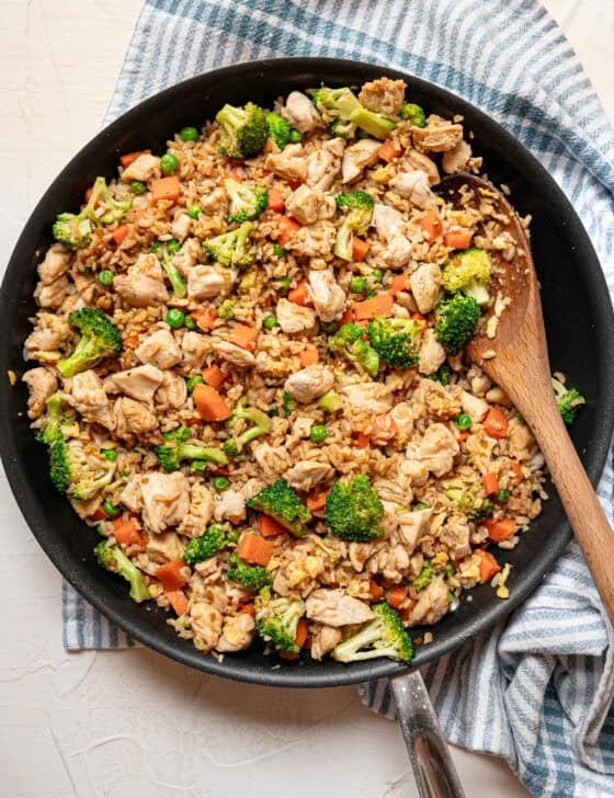 Chicken fried rice served with a wooden spoon out of skillet.