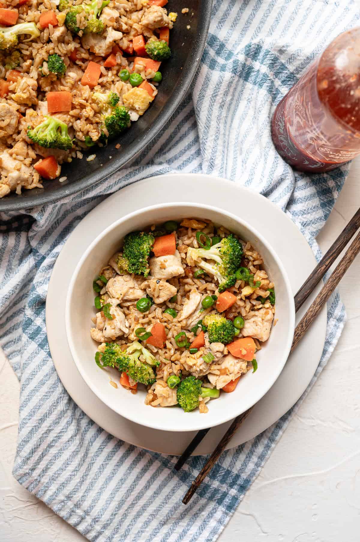 A bowl of chicken fried rice next to the skillet it was served from.
