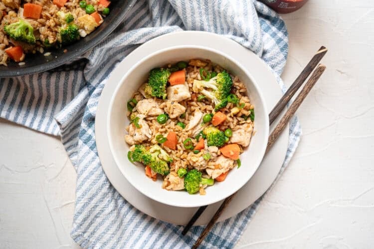 Chicken fried rice in a white bowl served with chopsticks.