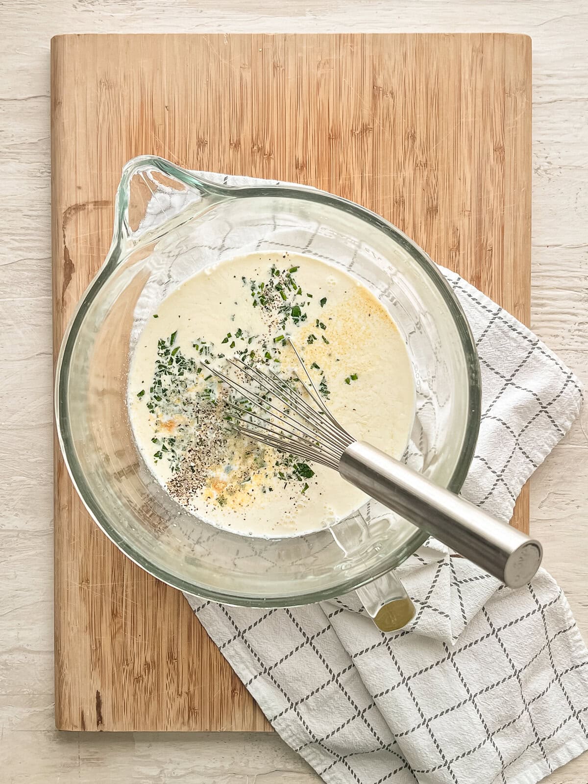 Eggs, milk, cream, and seasonings being whisked in a bowl for breakfast casserole.
