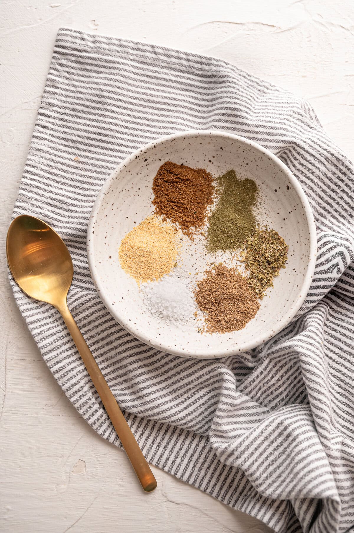 Six piles of ground seasonings in a small bowl ready to be mixed for oven roasted pork tenderloin.