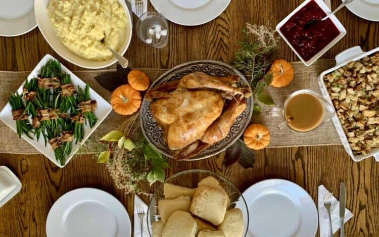Rachel's Thanksgiving table with turkey, gravy, mashed potatoes, green beans wrapped in bacon, and biscuits.