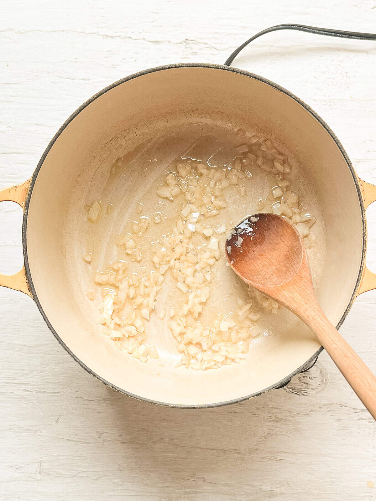 Diced onions being sauteed in a small Dutch oven.