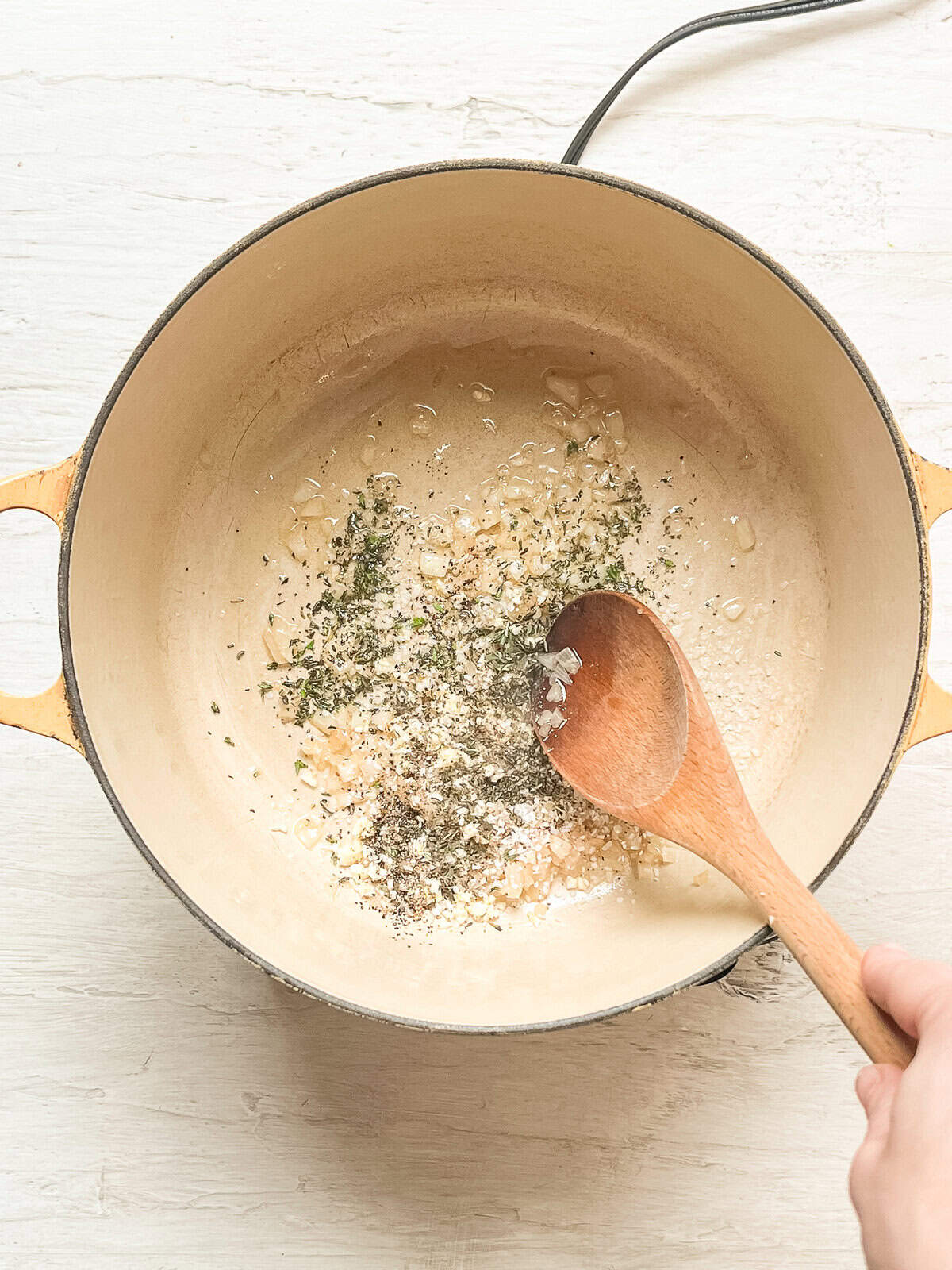 Dried seasonings added to sauteed diced onions in an enamel pot.
