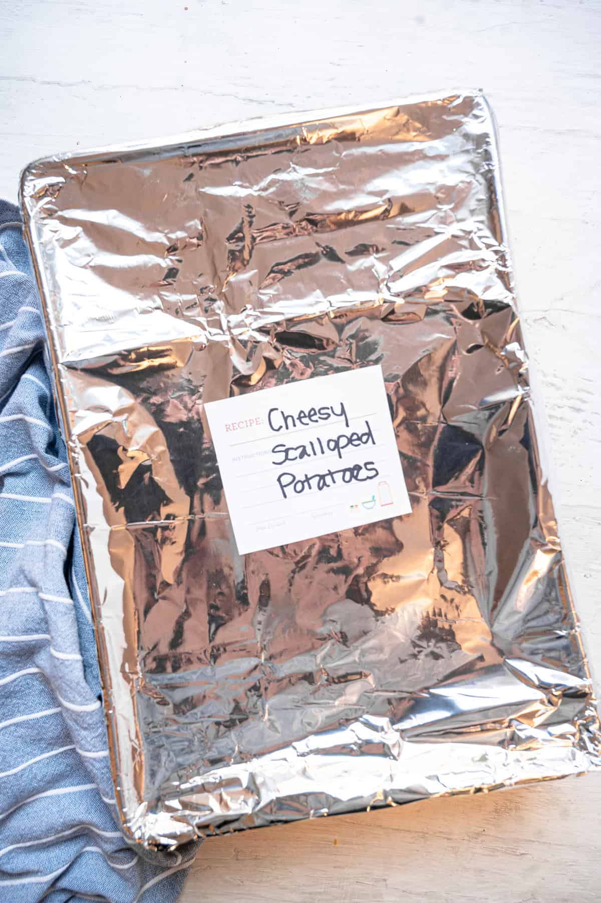 A 9x12 pan covered in foil and labeled, "Cheesy Scalloped Potatoes."