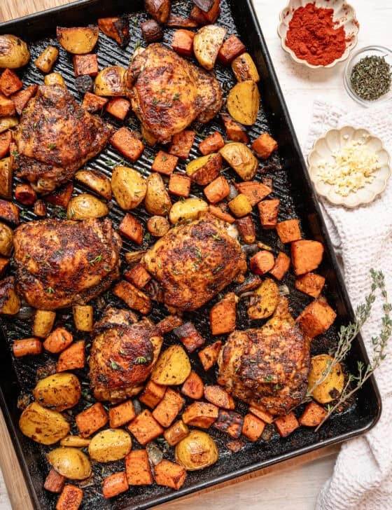 A sheet pan of chopped roasted veggies and chicken thighs fresh from the oven.