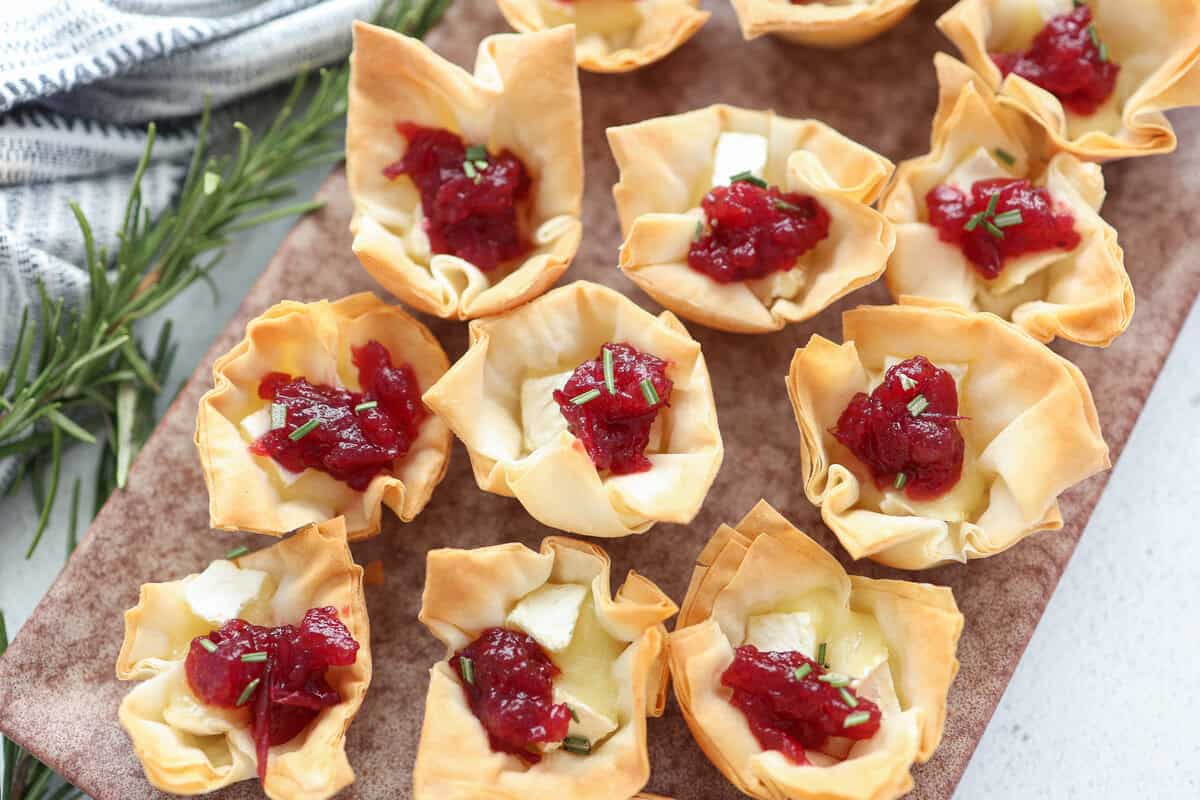 Mini phyllo cups with Brie cheese and cranberry sauce served on a platter.