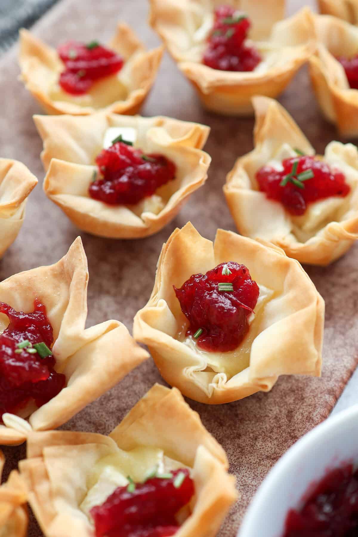 Cranberry sauce and brie cheese mini phyllo cups served on a platter.