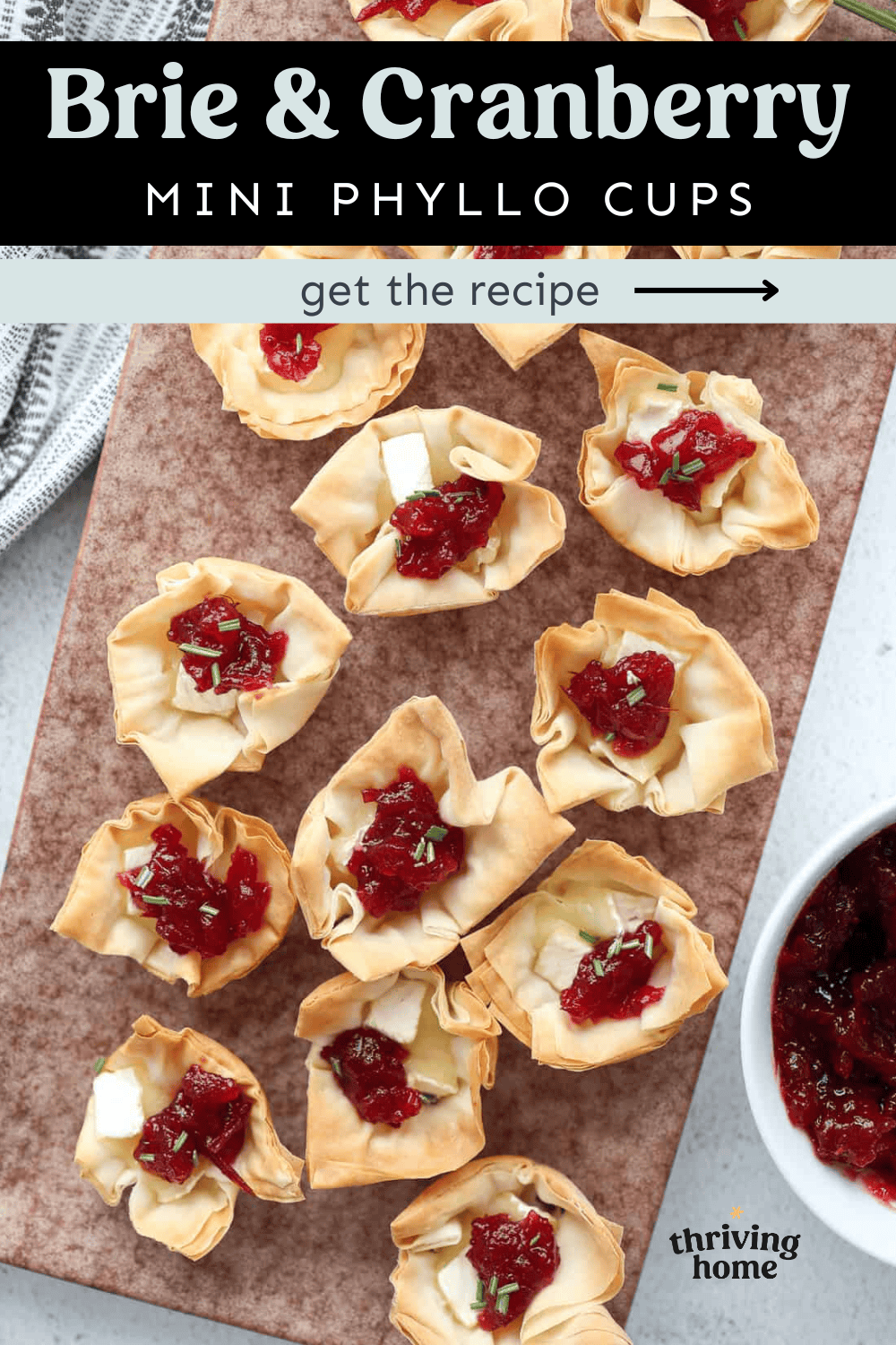 Wooden cutting board with brie and cranberry mini phyllo cups.