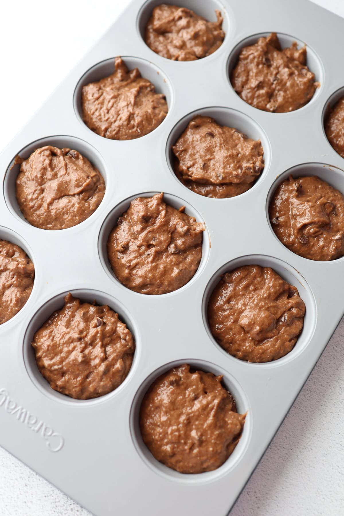 Chocolate banana muffin batter in a Caraway muffin tin.