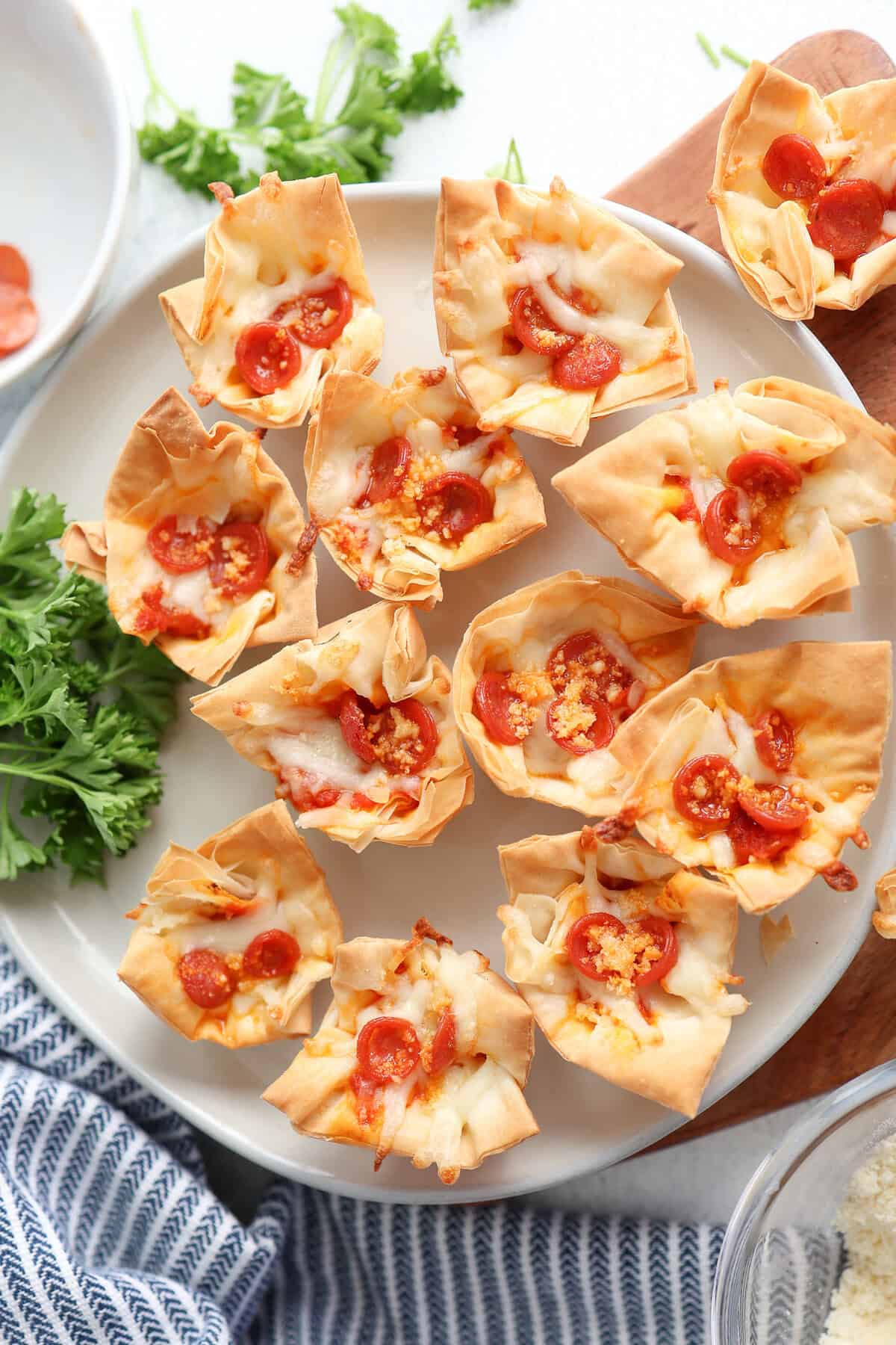 A platter of mini phyllo cups with pizza ingredients inside.