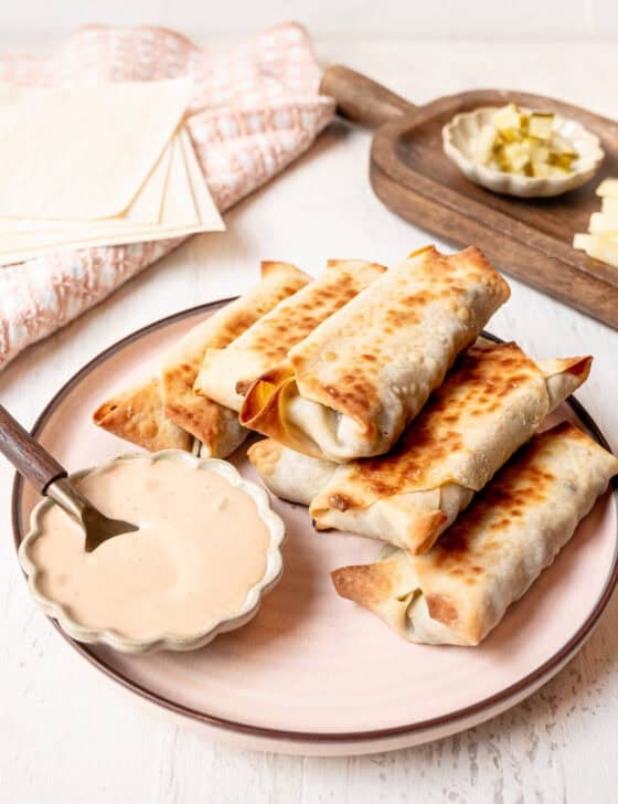 Cheeseburger egg rolls and a small bowl of secret sauce served on a platter.