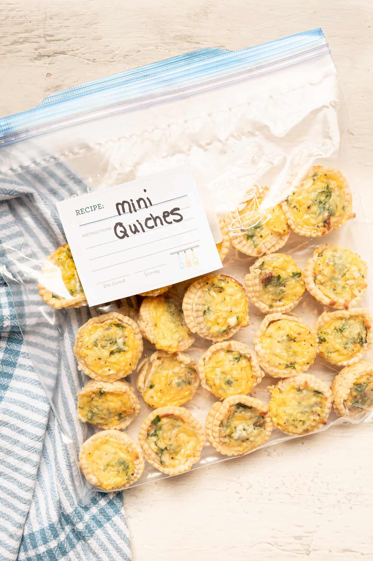 Fully cooked and cooled mini quiches lined up in a freezer bag ready for the freezer.