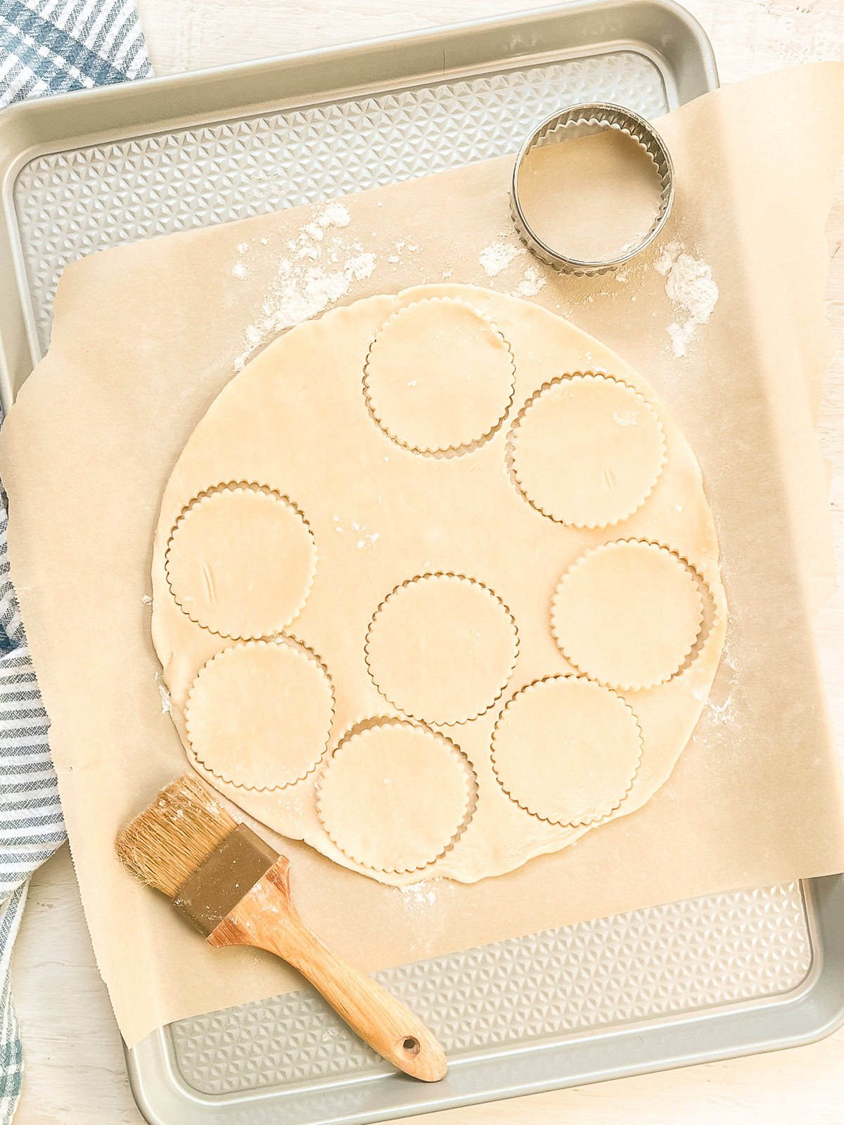 Pie crust being cut into small circles with a cookie cutter.