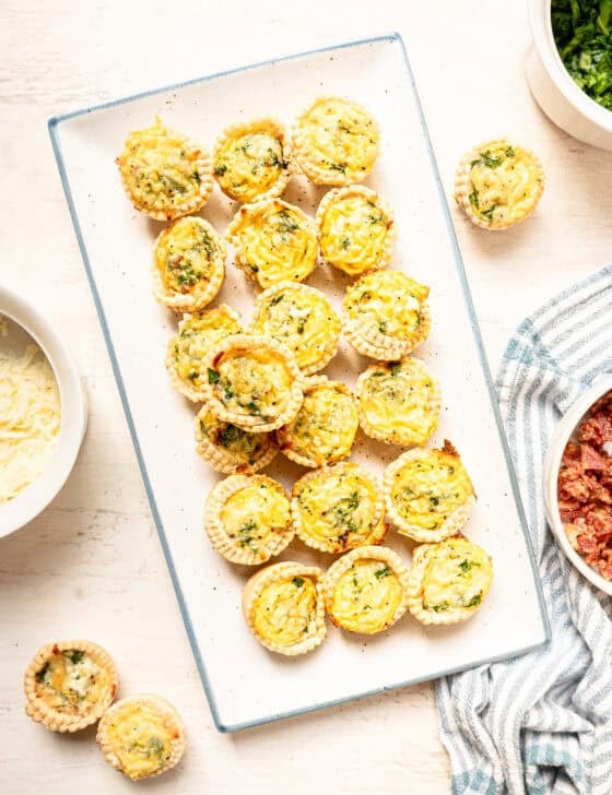 A platter of spinach and bacon mini quiche ready to eat.