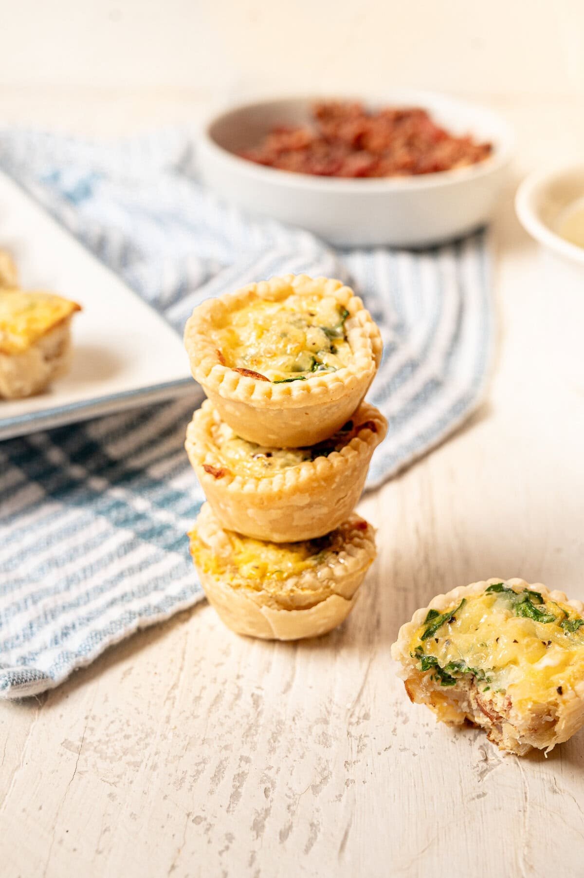 Mini quiche stacked up with another one split in half beside them.