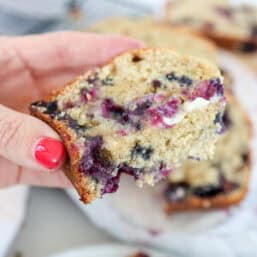A bite out of a slice of blueberry banana bread with butter.