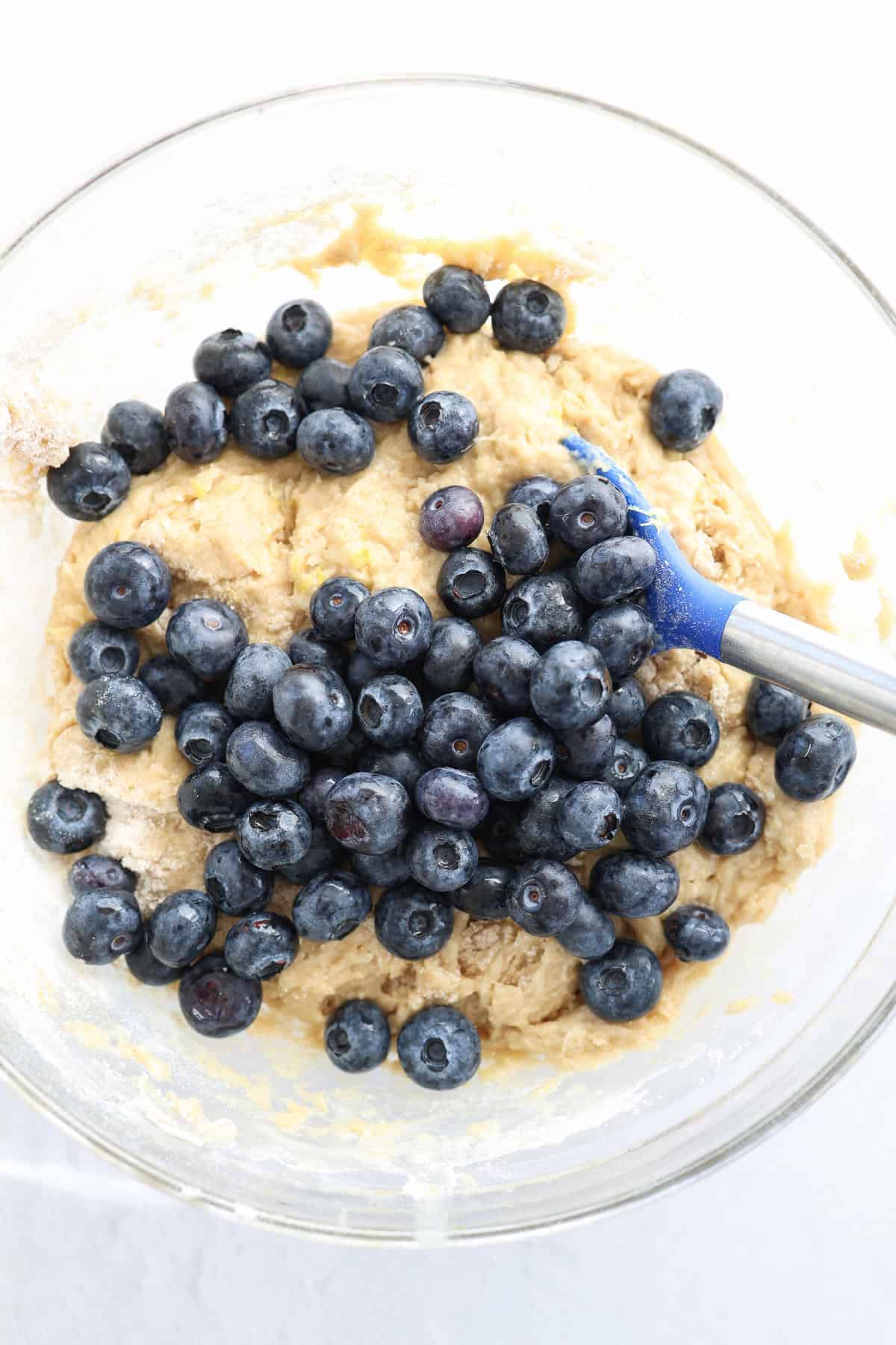 Fresh blueberries being folded into a sweet bread batter.