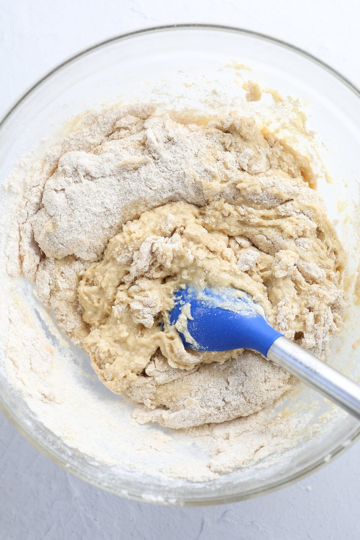 Wet and dry ingredients for sweet bread mixed together in a glass mixing bowl.