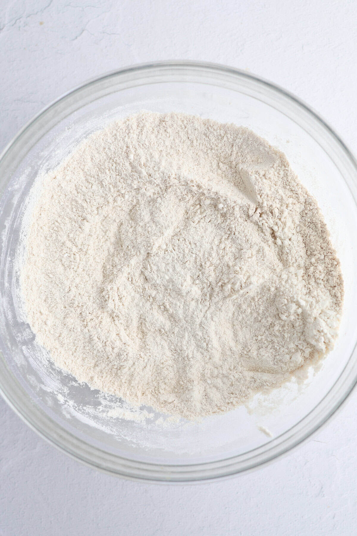 Dry ingredients for sweet bread in a glass mixing bowl.