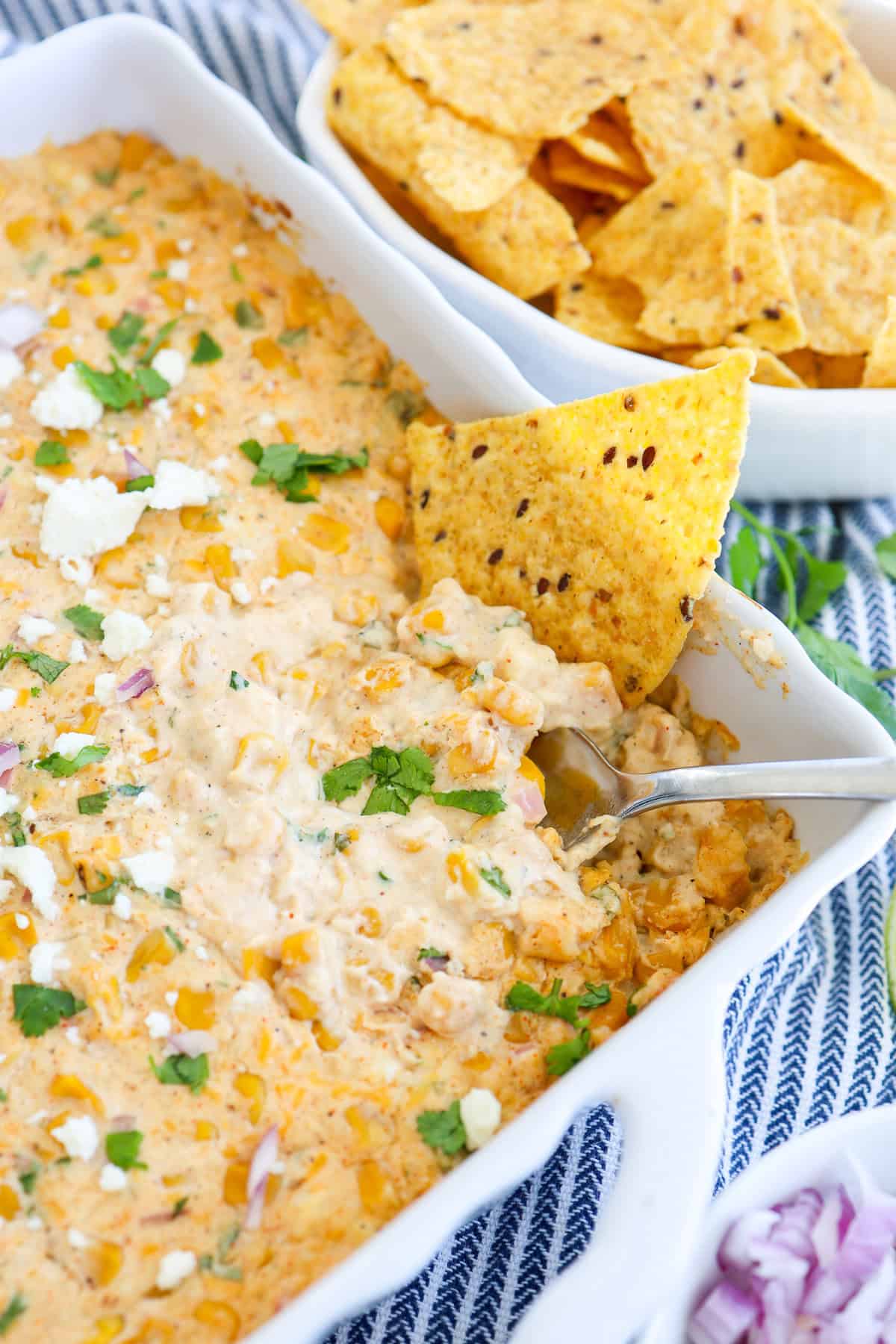 Mexican street corn dip on a white square pan.