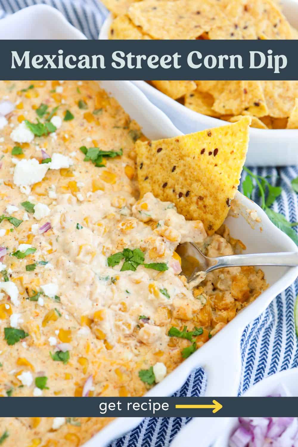 A tortilla chip dipped into a casserole dish of Mexican street corn dip.