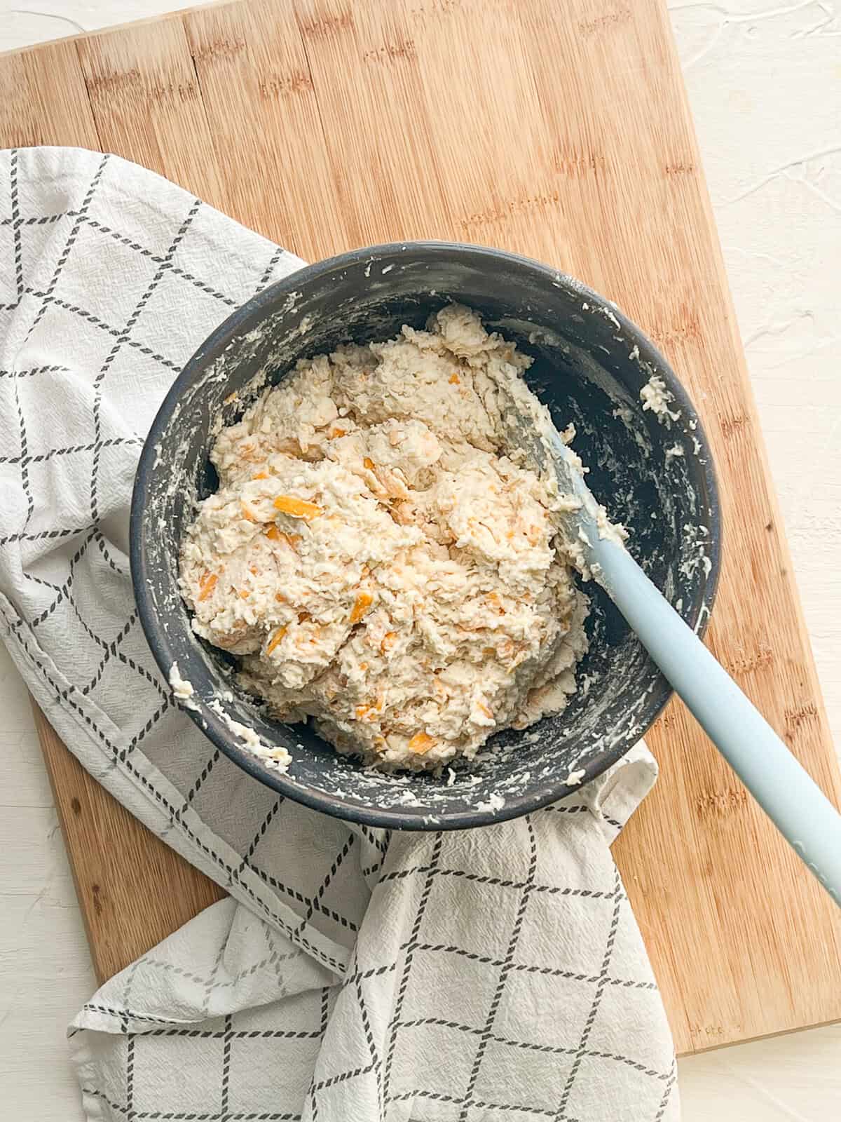 Cheddar cheese drop biscuit batter in a ceramic mixing bowl.