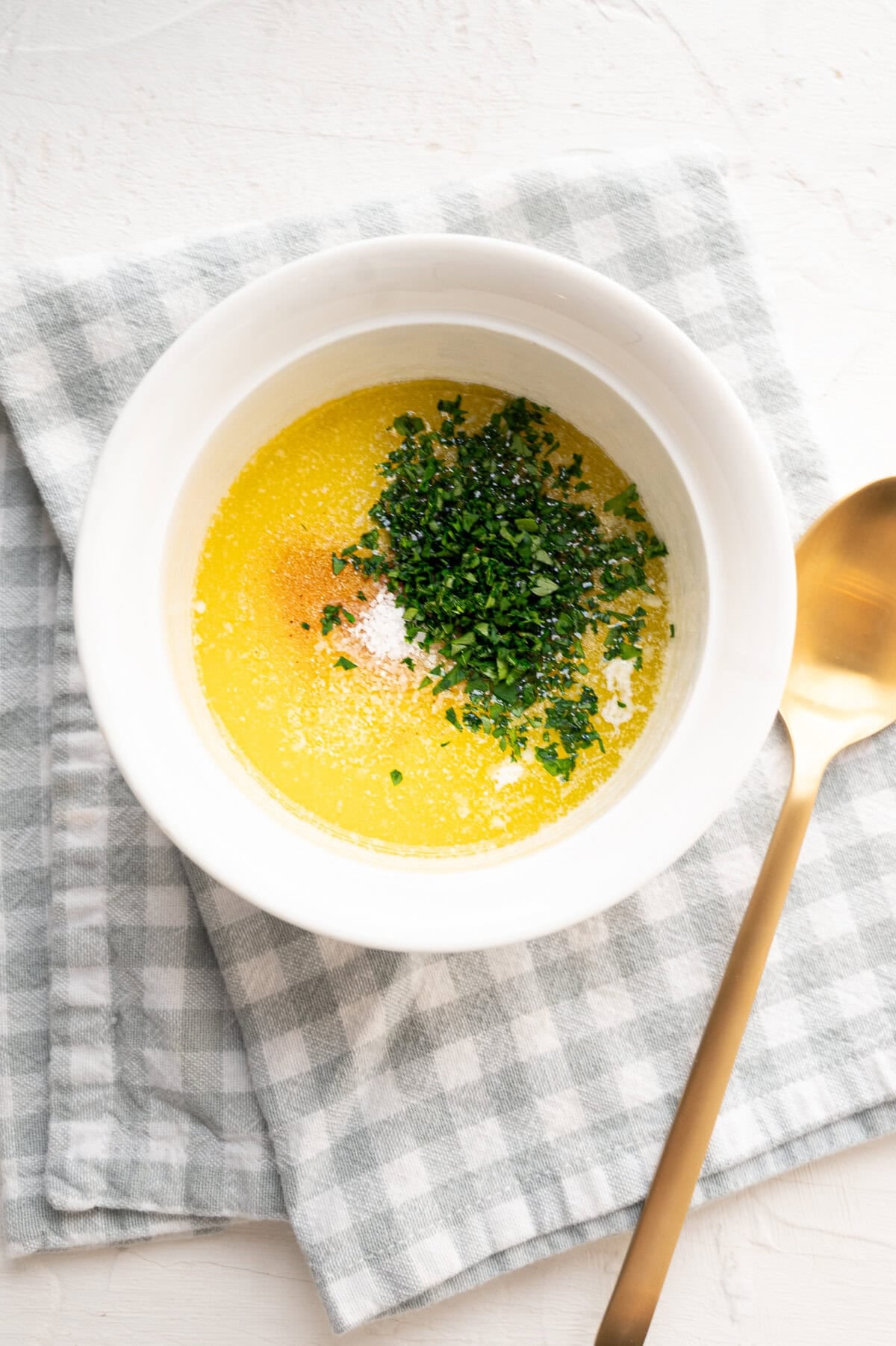 Melted butter, garlic powder, salt, and fresh parsley in a small bowl.