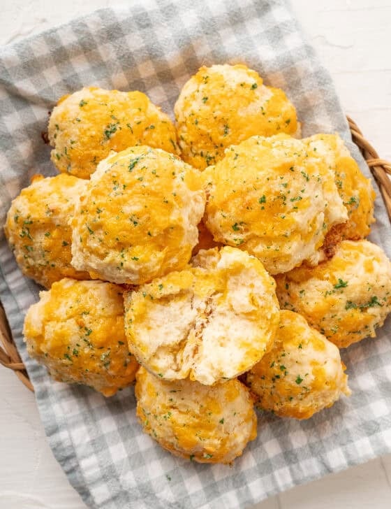 A pile of cheddar biscuits with the top one split in half.
