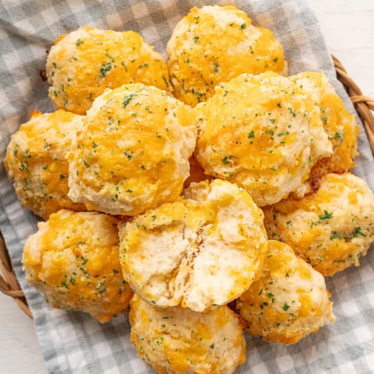 A pile of cheddar biscuits with the top one split in half.