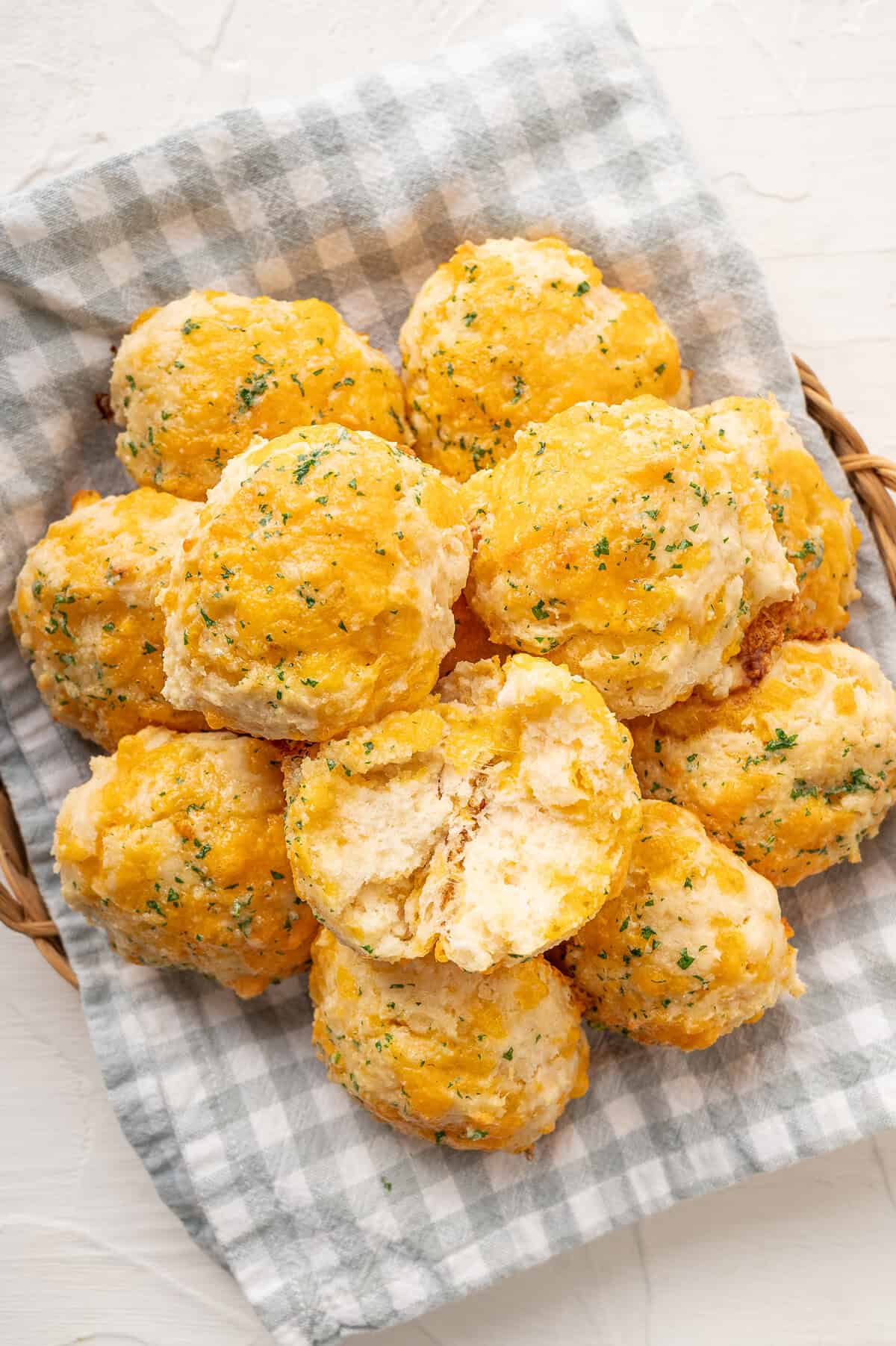 A pile of cheddar biscuits with the top one split in half.