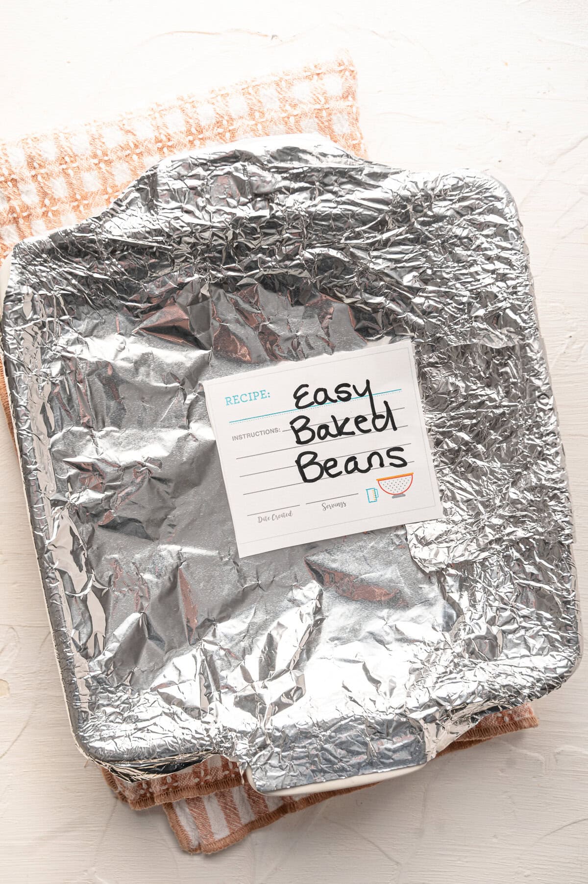 An 8x8 dish covered in foil and labeled Easy Baked Beans.