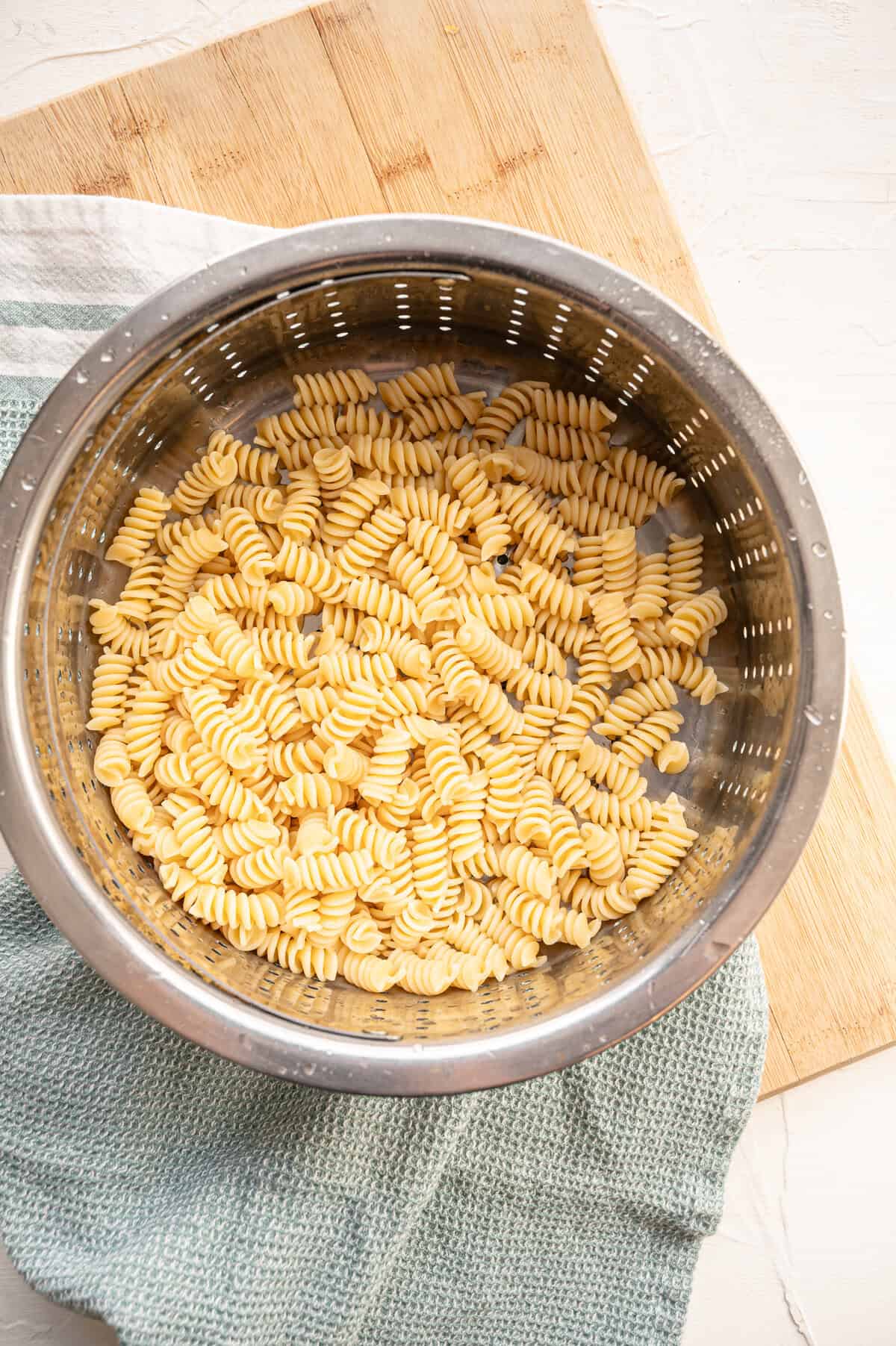 Cooked rotini pasta draining in a metal colander.