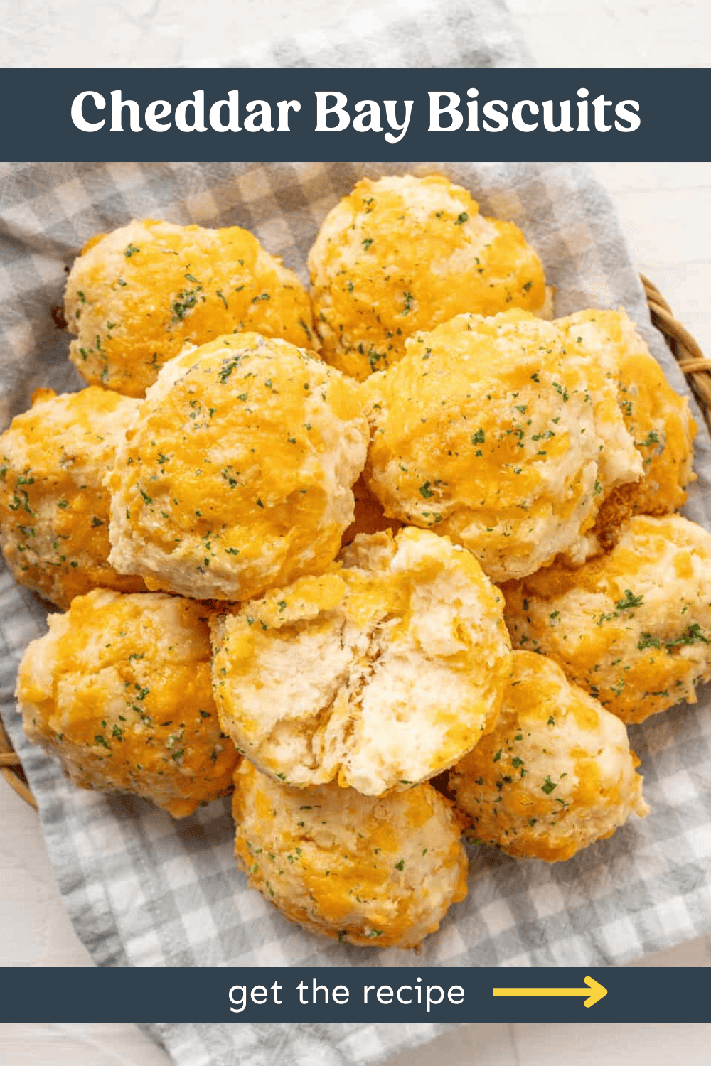 A basket of biscuits with cheddar cheese and herbs on top.