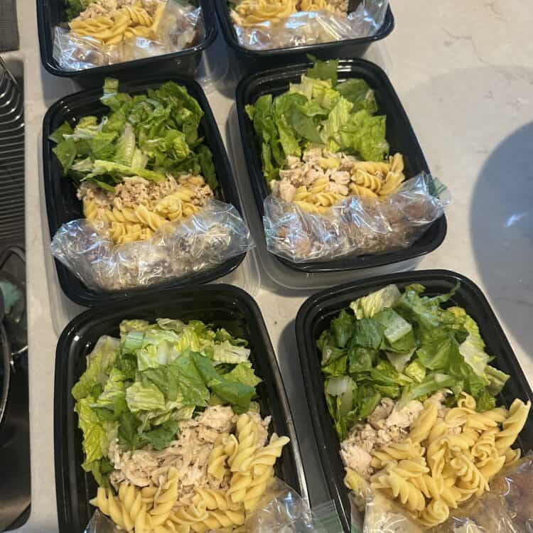 Small containers of Caesar Pasta Salad with chicken for meal prep.